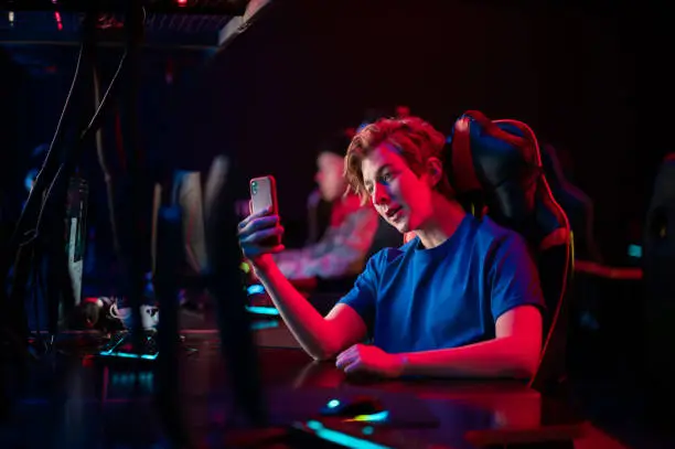 Photo of A young esports player records a video on his phone for his vlog from the training base of his team of gamers