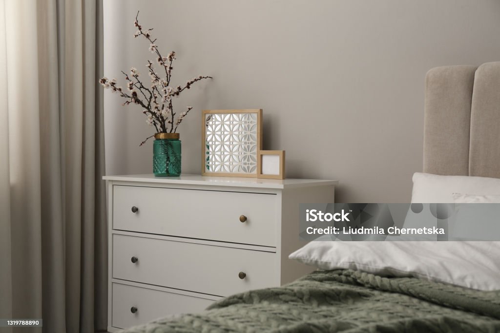 Flowering tree twigs and decor on white chest of drawers in bedroom Dresser Stock Photo
