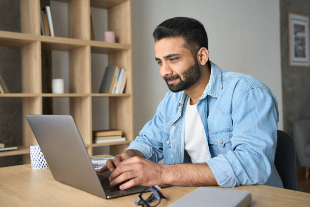 istock Young ethnic Hispanic businessman working from home office using laptop. 1319789977