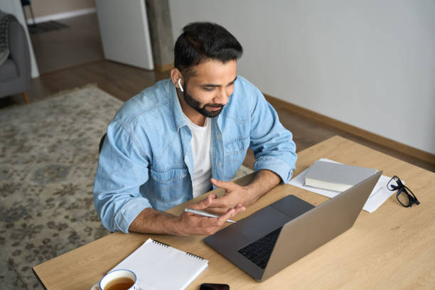 istock Young happy indian man having video call at home office using pc. Top view. 1319789979
