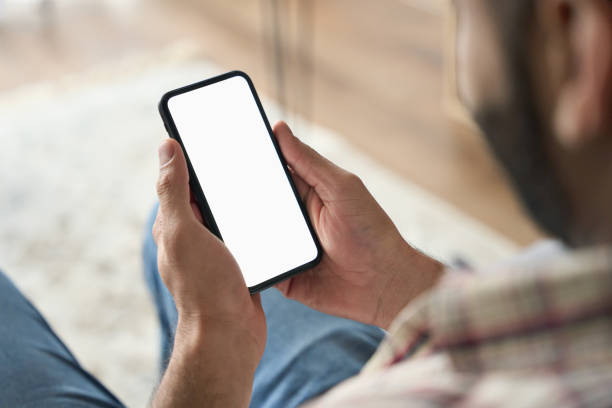 istock Male hands holding cellphone. Empty white screen. Over shoulder closeup view. 1319790034