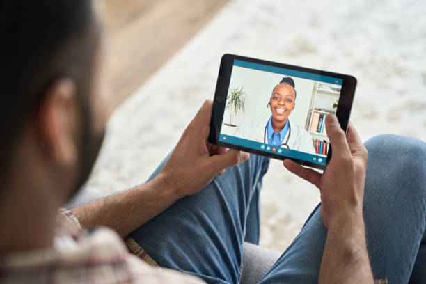 istock Young indian man having videocall with female black doctor using tablet. 1319790065