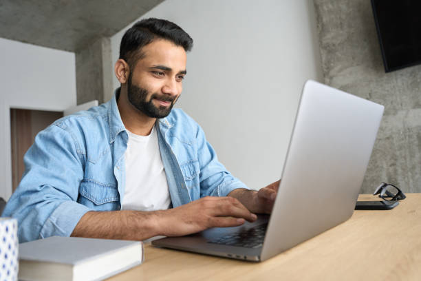 istock Young happy Hispanic businessman working from home office using laptop. 1319790152