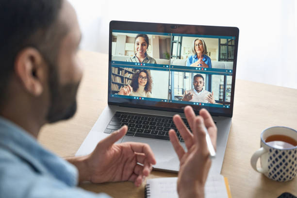 Over shoulder view of indian man having video call with diverse people on pc. Latin indian businessman having virtual team meeting group call chatting with diverse people in customer support. Video conference call on computer with manager and employees.Â  Over shoulder view. business laptop photos stock pictures, royalty-free photos & images