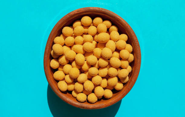 cheese coated salted peanuts in a brown bowl on bluea background. fried peanut grains with a coating of savory spices - beer nuts imagens e fotografias de stock