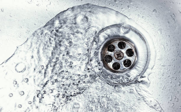 sink hole water drain down on stainless steel kitchen sink hole. top view sewer in washbasin. household plumbing. cleaning and hygiene concept. flowing photos stock pictures, royalty-free photos & images