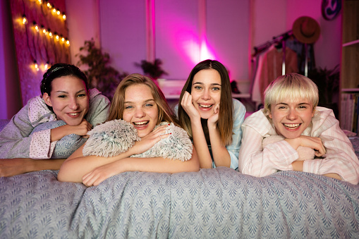 Portrait of four young Caucasian women lying on the bed and looking at the camera.