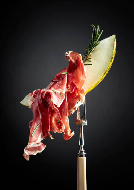istock Melon with prosciutto and rosemary on a black background. 1319793089
