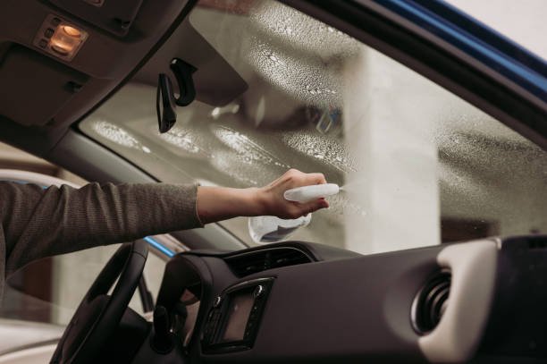 Woman spraying and cleaning inside of windshield