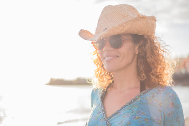 istock Smiling Woman Looking Away While Wearing Hat Against Sea 1319795651