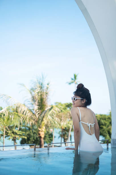 istock Woman Standing By Swimming Pool Against Sky 1319796934