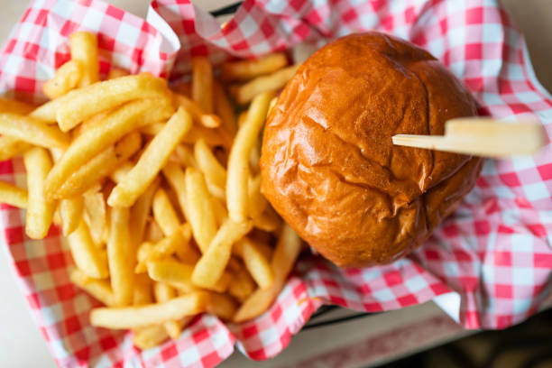 Close up color image depicting a topdown high angle view of a burger in a glazed bun with a side of French fries.