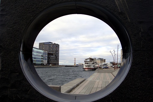 The glimpse of a canal seen from a porthole with a ship docked at the quay and a glimpse of some buildings