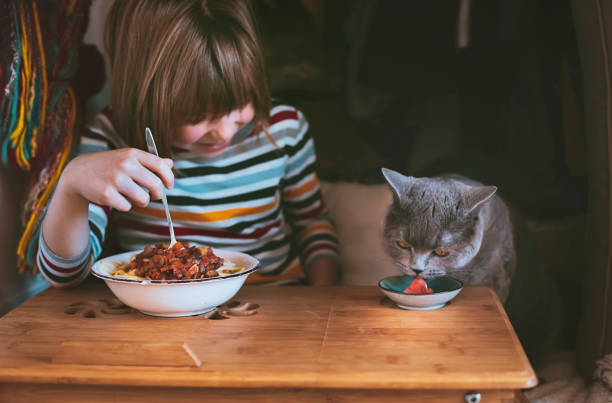 istock Happy little boy eating spaghetti with his cat 1319798741