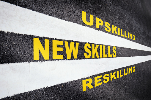 New skills, reskilling and upskilling written on asphalt road with white marking line