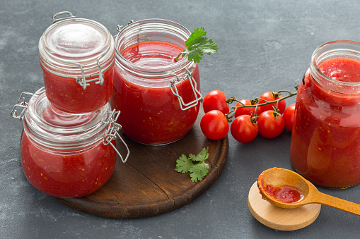 Tomato sauce in glass jars close up on a dark background