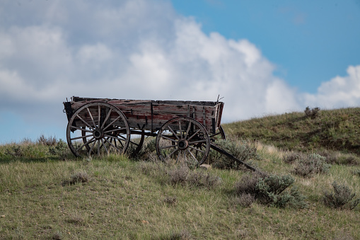 Old wooden wagon sitting on a Montana hilltop with beautiful clouds in the background, in western USA. Nearest city is Billings, Montana.