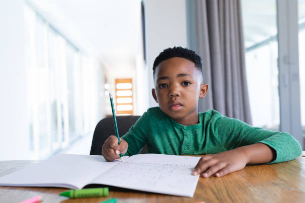 istock African american boy in online school class, writing in his notebook 1319810520