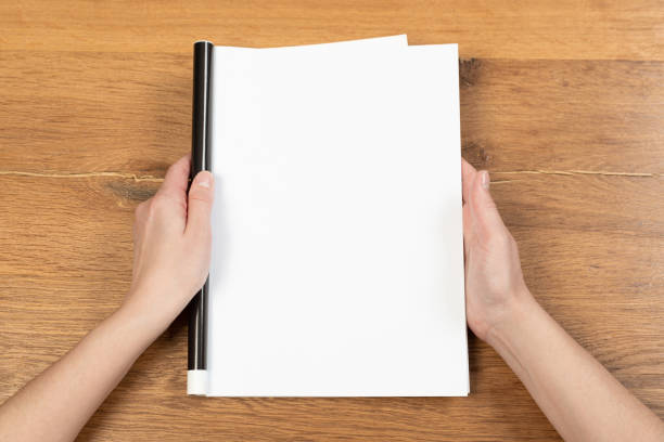 istock Woman's hands open empty catalog, magazines, book mockup on wooden table 1319812136