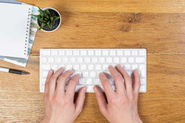 istock An image of a woman's hand is typing on a white keyboard on a wooden table. Selective focus 1319812144