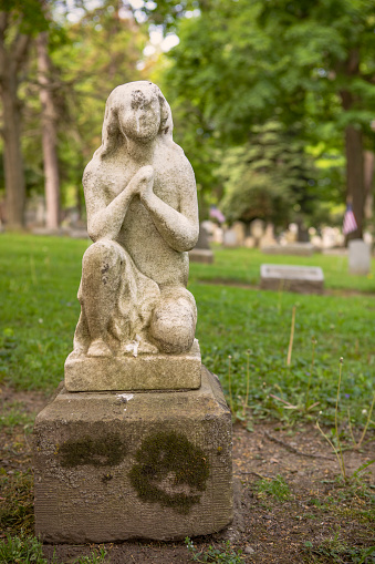 A creepy old tombstone of a figure kneeling in prayer.
