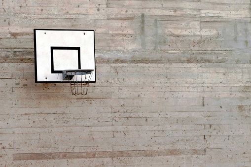 Cement wall with a basketball hoop with a lot of copy space.