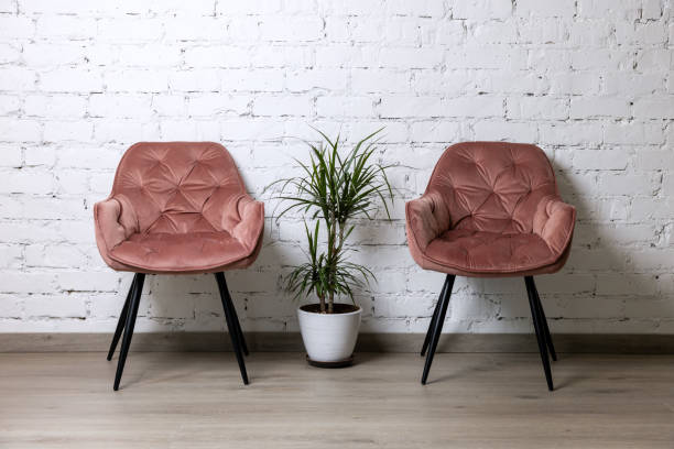 two upholstered pink chairs and palm plant by white brick wall. minimalism interior two upholstered pink chairs and palm plant by white brick wall. minimalism interior upholstered furniture stock pictures, royalty-free photos & images