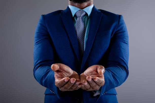 section moyenne de l’homme d’affaires afro-américain avec les mains cupped sur le fond gris - mettre ses mains en coupe photos et images de collection