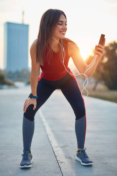 istock Modern young woman with cellphone making pause during jogging exercise. 1319815450
