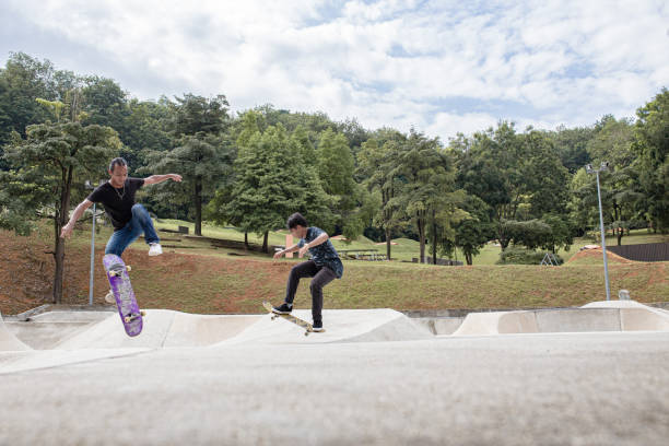 asiatischer skateboarder fängt mitten in der luft in einem skatepark - extreme skateboarding action balance motion stock-fotos und bilder