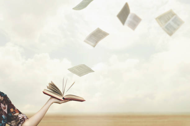 istock pages fly free in the sky from a book held open by a woman 1319818155