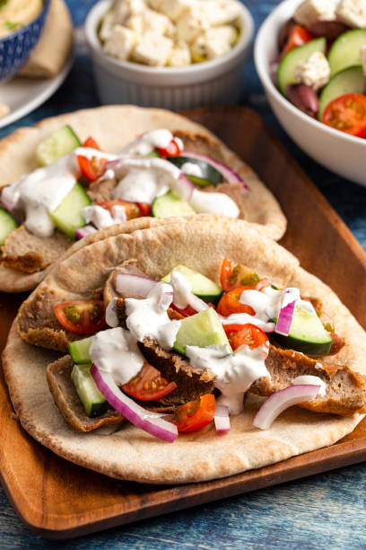 istock Two Gyros with Vegetables and White Garlic Sauce on a Rustic Wooden Table 1319820240
