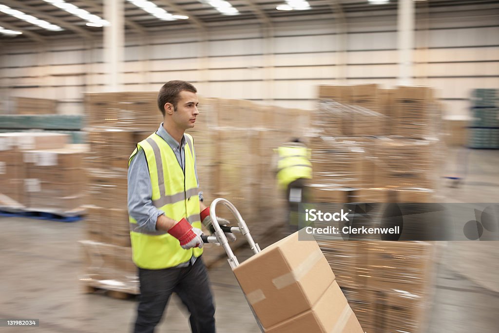 Jeune homme Travailleur poussant de boîtes en carton de la main de camion au - Photo de Diable - Chariots et charrettes libre de droits