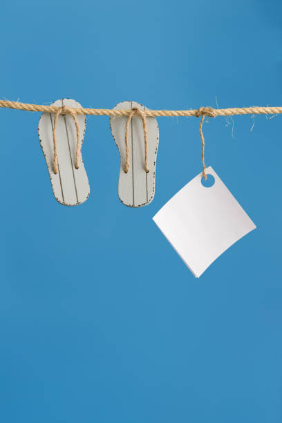 istock Summer composition with marine items hanging on string. Sea toys slipper and empty white paper 1319822791
