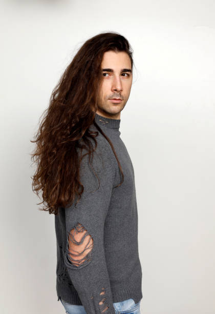 istock Attractive young guy with very long curly hair is posing in studio. 1319824573