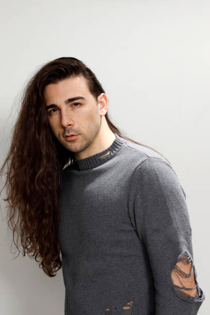istock Attractive young guy with very long curly hair is posing in studio. 1319824676