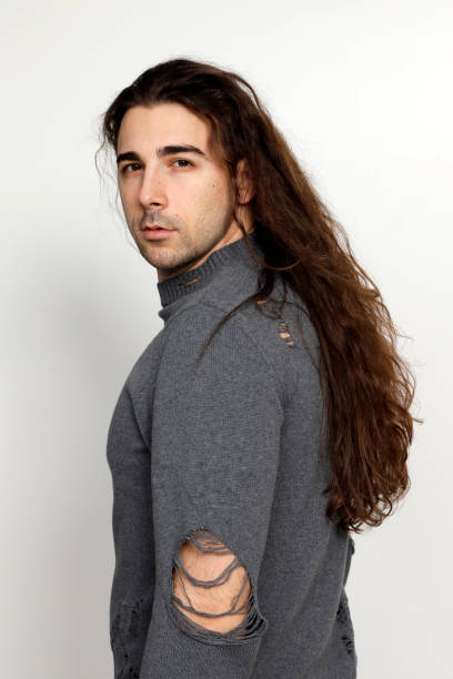 istock Attractive young guy with very long curly hair is posing in studio. 1319824686