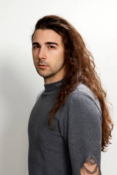 istock Attractive young guy with very long curly hair is posing in studio. 1319824732