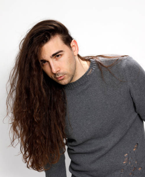 istock Attractive young guy with very long curly hair is posing in studio. 1319824883