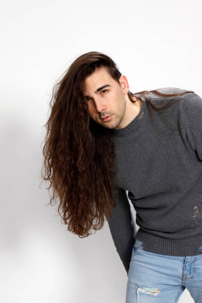 istock Attractive young guy with very long curly hair is posing in studio. 1319825077