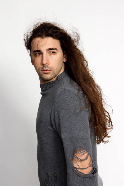 istock Attractive young guy with very long curly hair is posing in studio. 1319825080