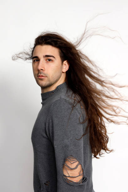 istock Attractive young guy with very long curly hair is posing in studio. 1319825192