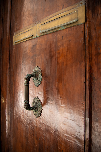 Old wooden door with shiny metal handle. Door handle closeup. Venice, Italy