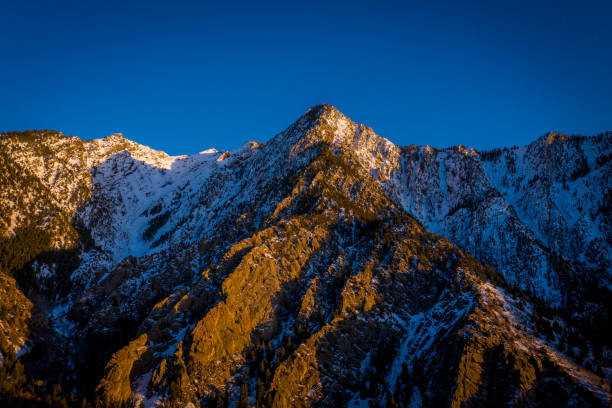 istock Snow Covered Mountain Peak With Orange Glow of Sunset 1319828135