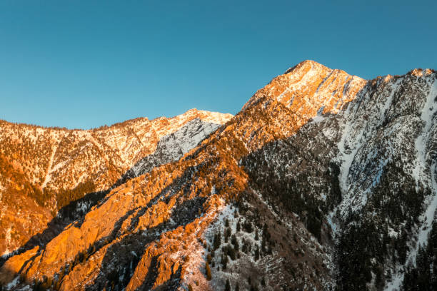 istock Snow Covered Mountain Peak With Orange Glow of Sunset 1319828259