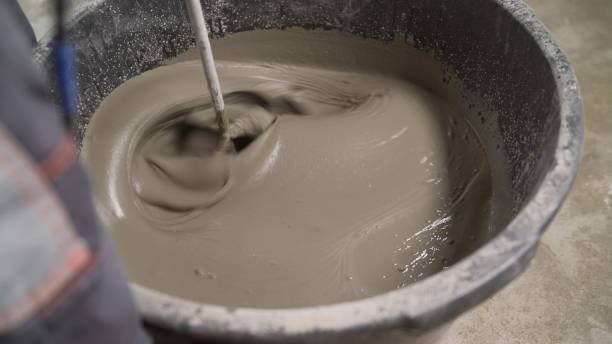 istock Mixing plaster solution in a bucket using electric drill. Construction and renovation concept. Mix the solution with a self-leveling floor in a bucket. The worker mixes the solution in a bucket using a mixer 1319828264