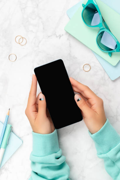 istock Female hand holding mobile phone on marble background 1319828266