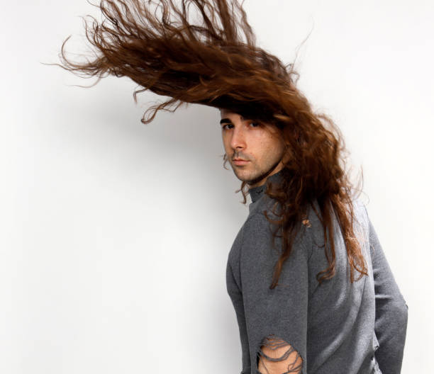 istock Attractive young guy with very long curly hair is posing in studio. 1319828285