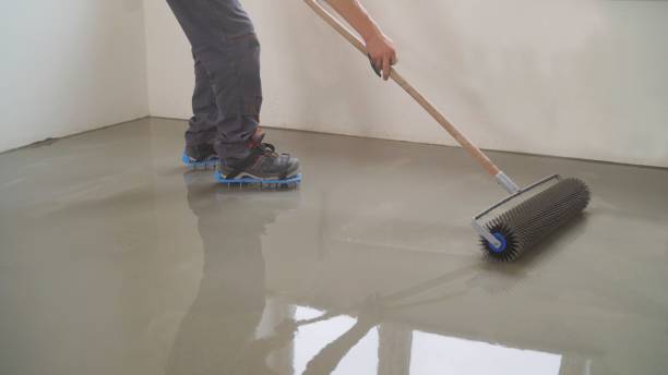 istock A worker rolls out the liquid floor with a trowel. Squeegee for distributing the mixture. The worker levels the liquid floor. Finishing works - Needle roller for bulk floor 1319828853