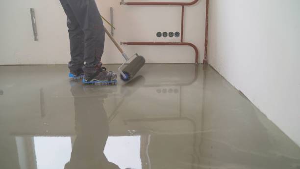 istock A worker rolls out the liquid floor with a trowel. Squeegee for distributing the mixture. The worker levels the liquid floor. Finishing works - Needle roller for bulk floor 1319828863
